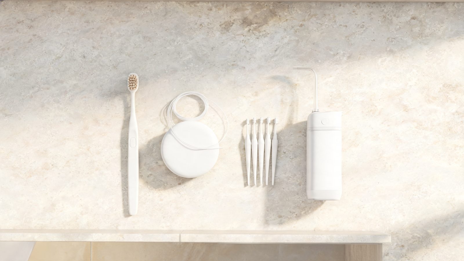 Soft toothbrush, dental floss, interdental brushes and a water flosser on a bathroom counter